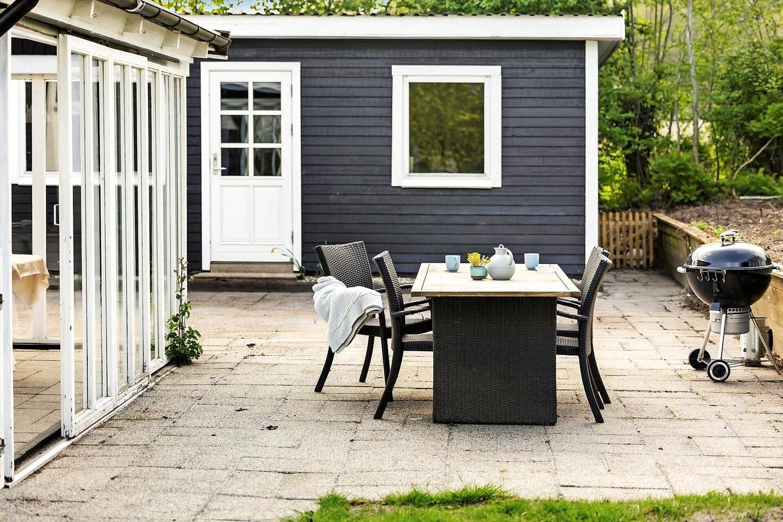 Haus mit weißem Zaun, Grill und Glasveranda im Freien.