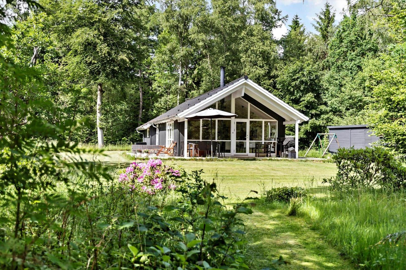 Ein Haus mit großem Glasbereich und Terrasse im Grünen.