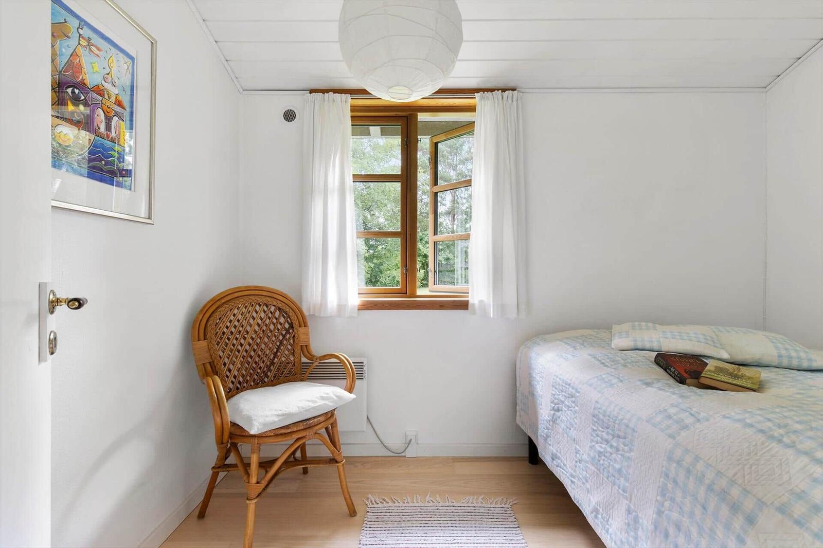 Ein Schlafzimmer mit einem Bett, einem Stuhl und einem Fenster.