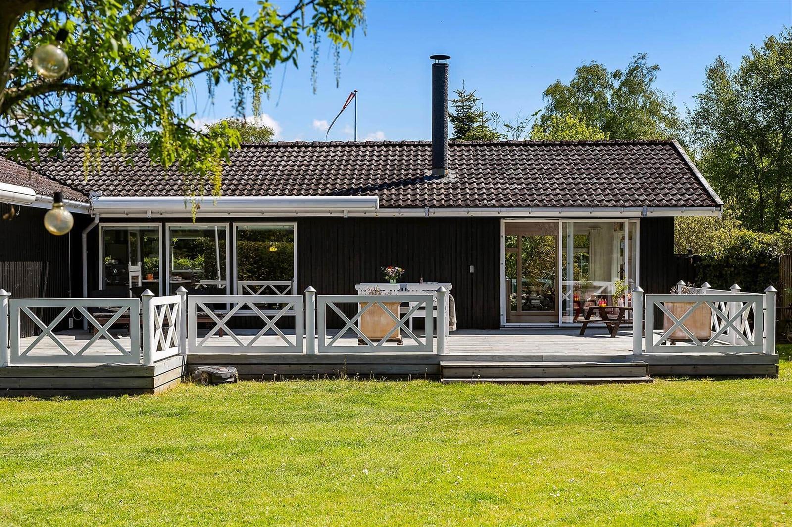 Ein Haus mit Terrasse, Garten und Schornstein. Durchgehende Glasfronten.