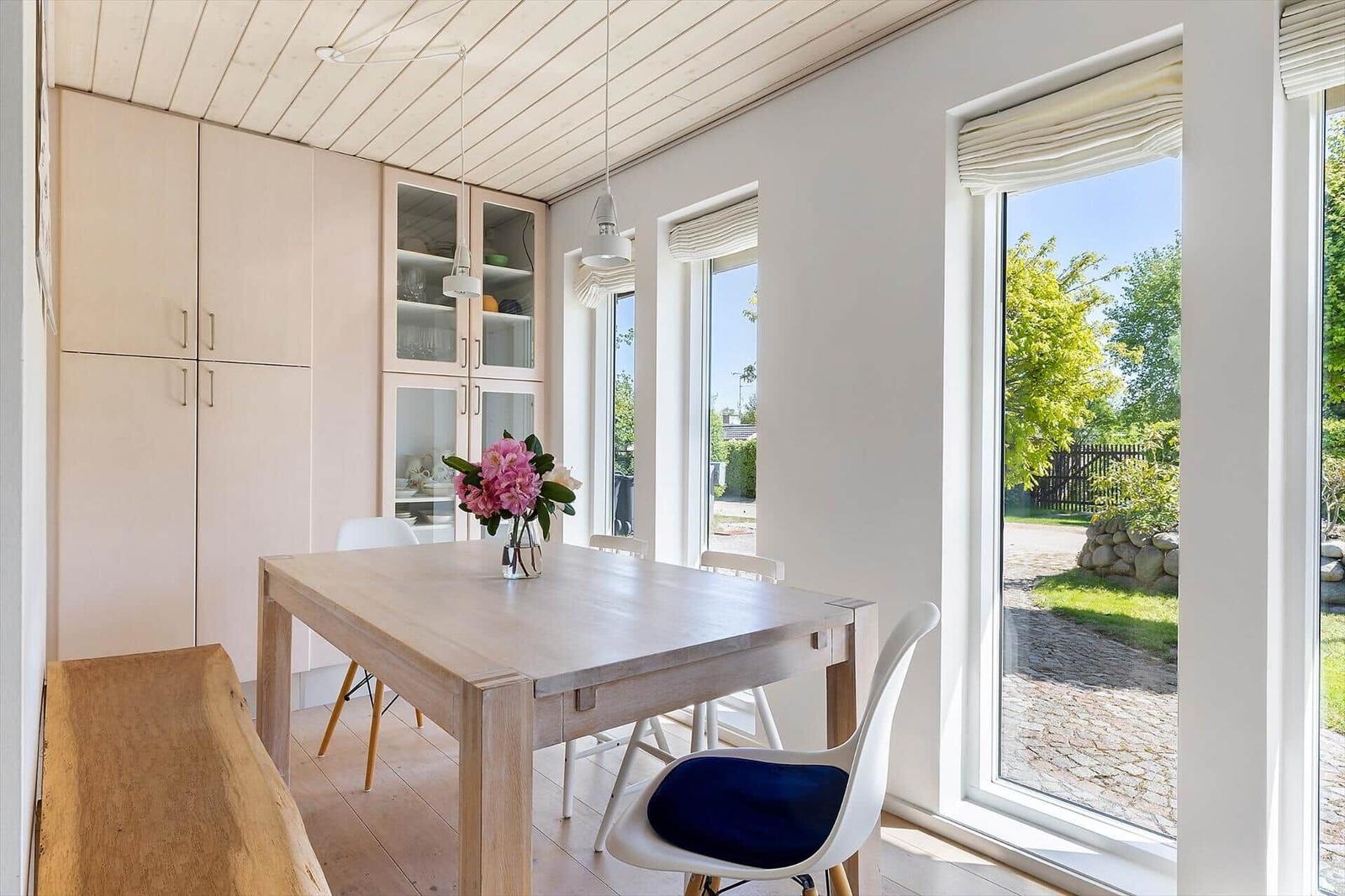 Esszimmer mit Holztisch, weißen Stühlen und Blick auf Garten.