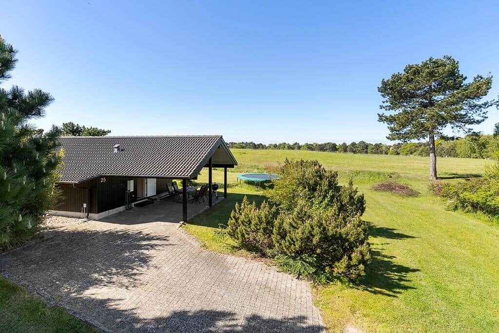 Haus mit Terrasse, Grillplatz und Pool auf grünem Grundstück mit Bäumen.
