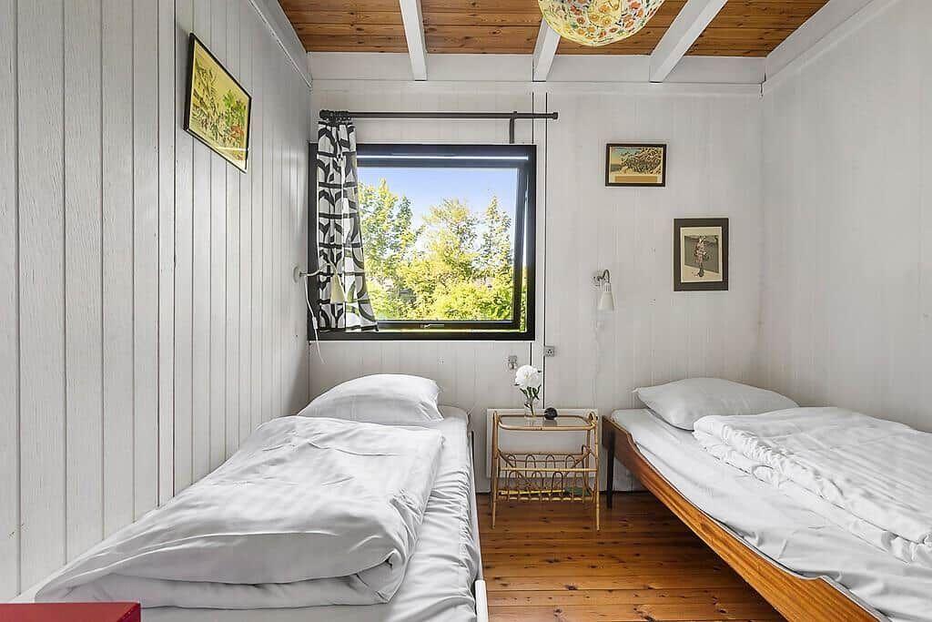 Zwei Einzelbetten, Fenster mit Blick auf Bäume, Holzboden und Wandbilder.
