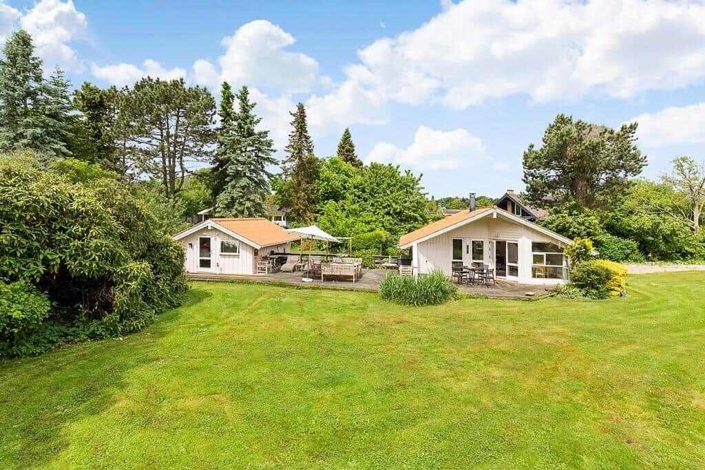 Zwei Häuser mit Terrassen und Garten unter Bäumen.