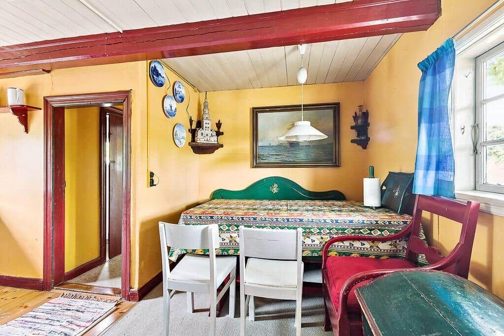 Schlafzimmer mit Bett, Tisch und Stühlen. Wand mit Bild und dekorativen Tellern.