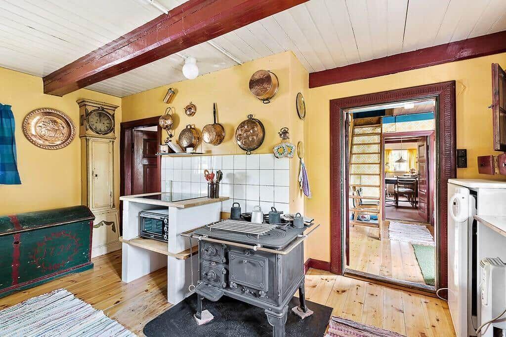 Küche mit Holzboden, Kaminofen und Wandbehängen.