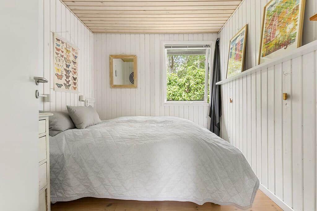 Schlafzimmer mit Bett, Fenster und Wanddekoration.