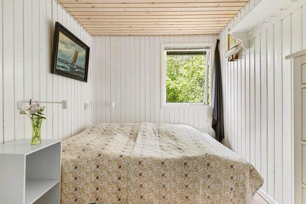 Schlafzimmer mit Bett, Fenster und Wandbild.