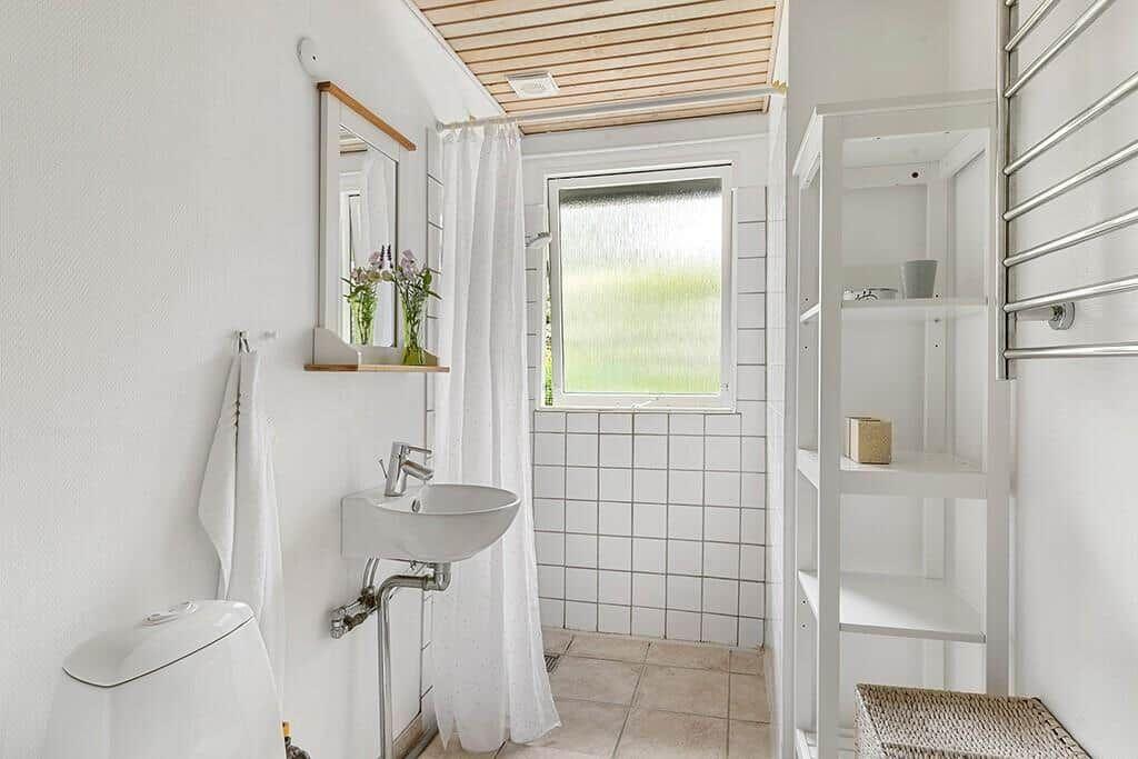 Badezimmer mit Waschbecken, Toilette, Dusche und Fenster.