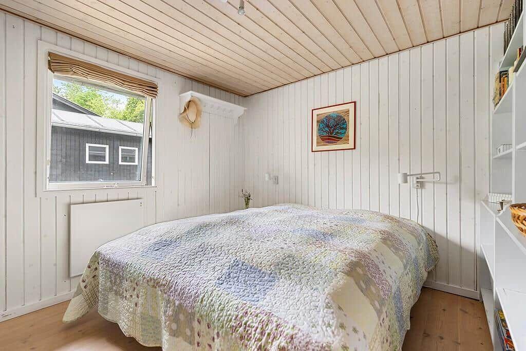 Schlafzimmer mit Bett, Fenster und weißen Wänden.