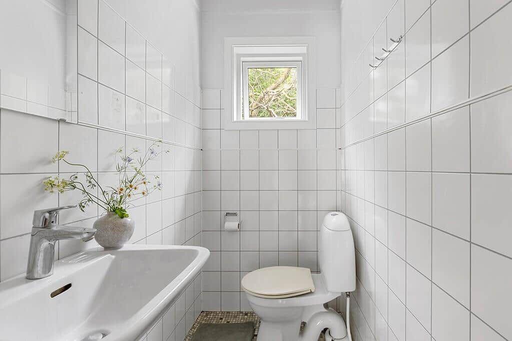 Badezimmer mit Toilette, Waschbecken und kleinem Fenster.