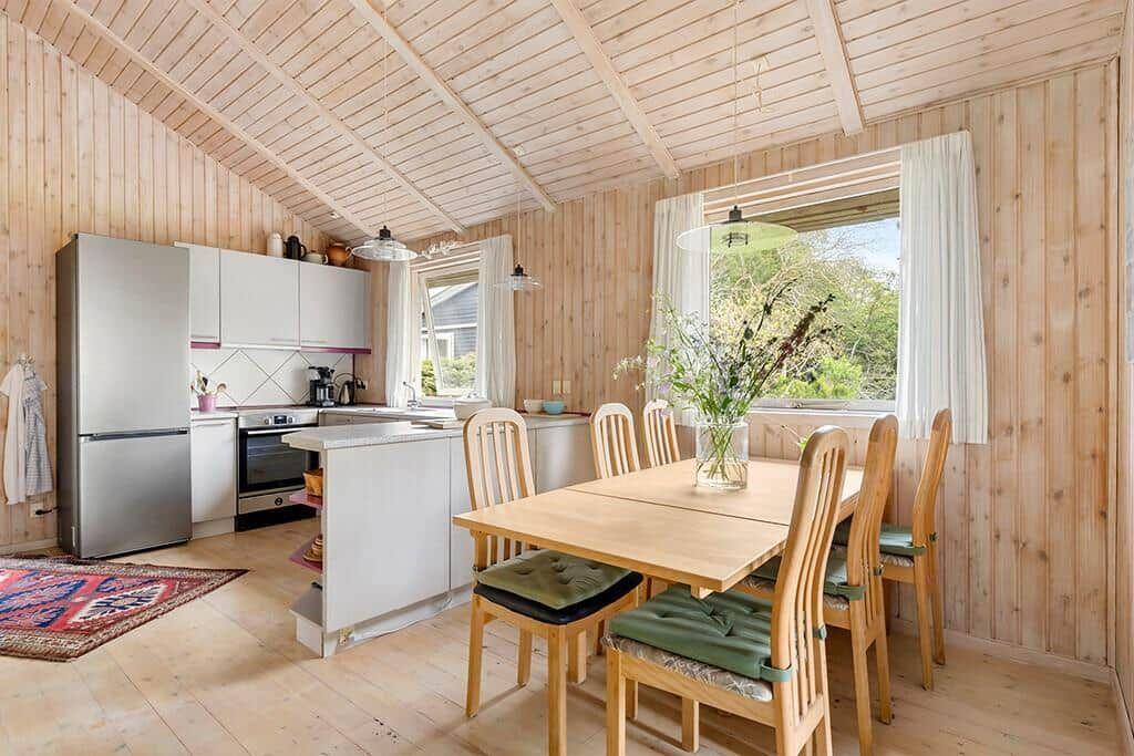 Küche und Essbereich mit Holzwänden, Tisch, Stühle und Fenster.