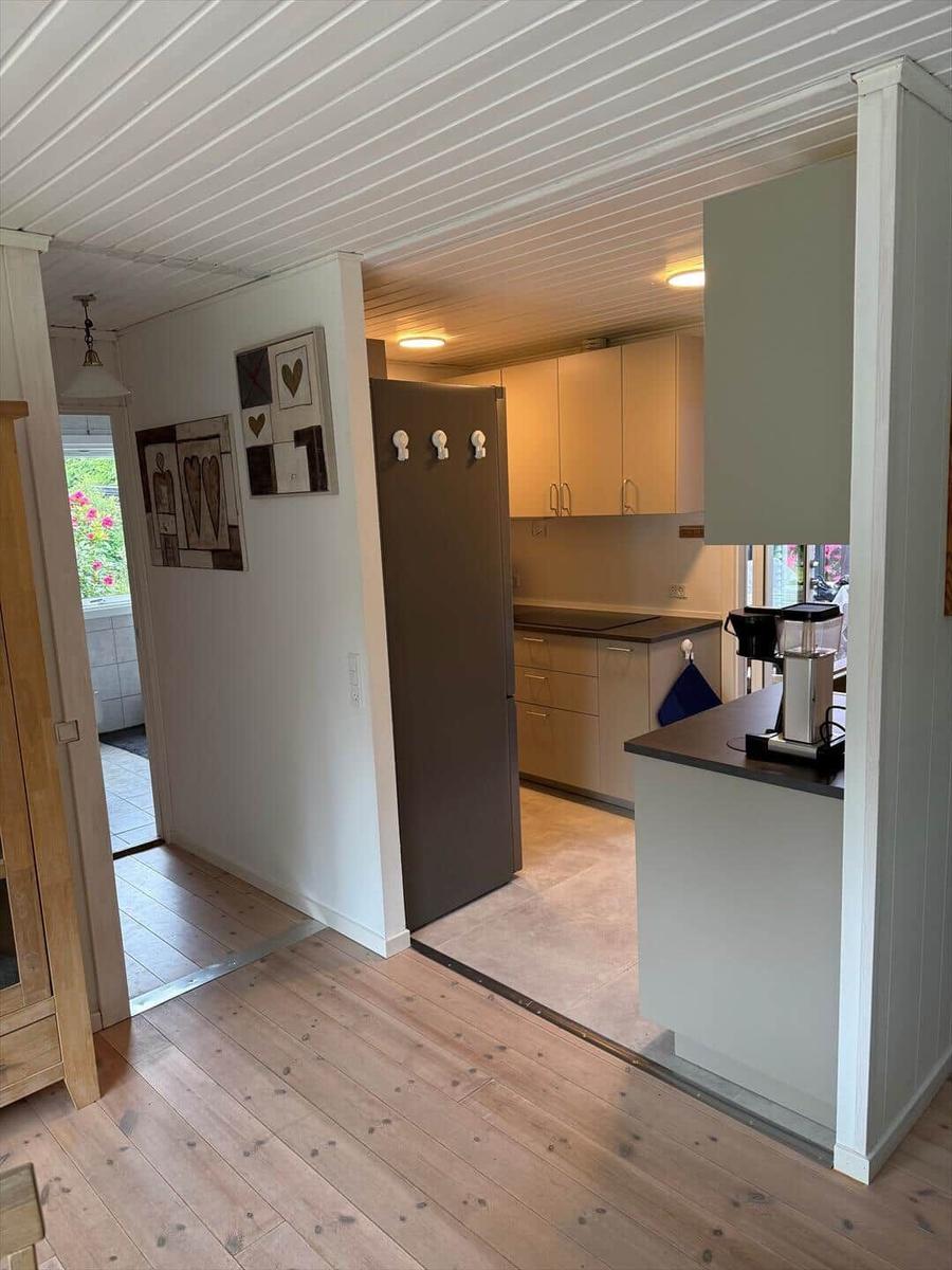 Küche mit Holzboden und Kühlschrank. Blick in den Wohnbereich.