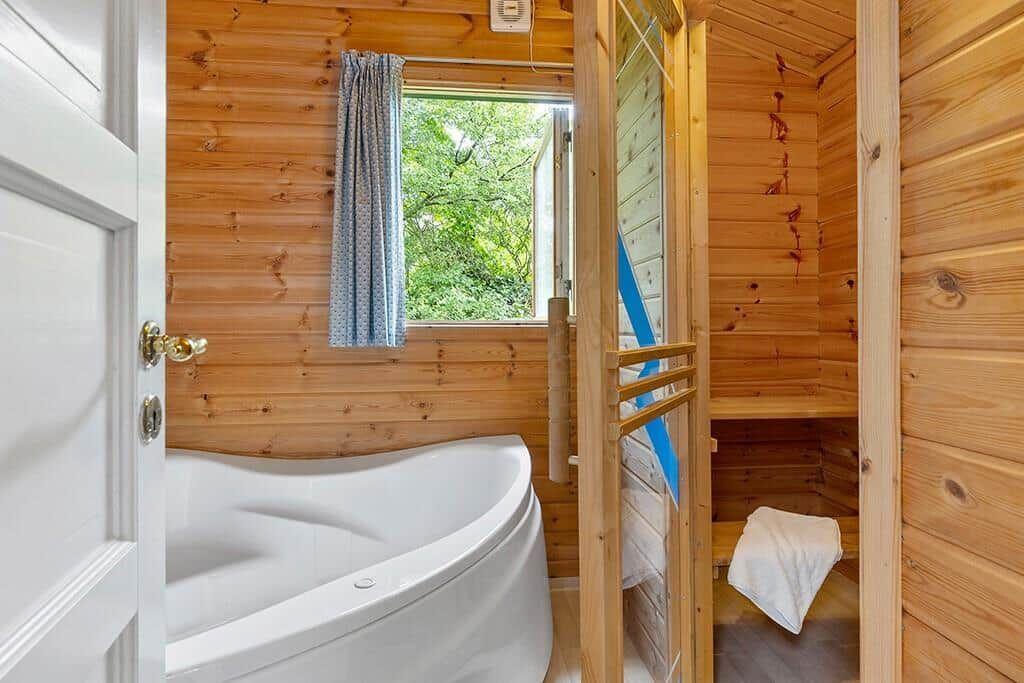 Bad mit Whirlpool und angrenzender Sauna mit Holzwand und Fenster.