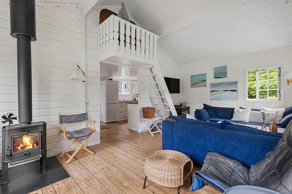 Wohnzimmer mit Kamin, blauem Sofa und Treppe zur Galerie.