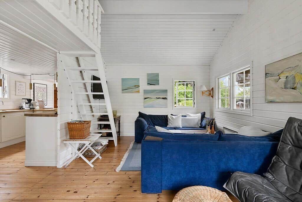 Wohnzimmer mit blauem Sofa, Holzboden und Treppe zur oberen Etage.
