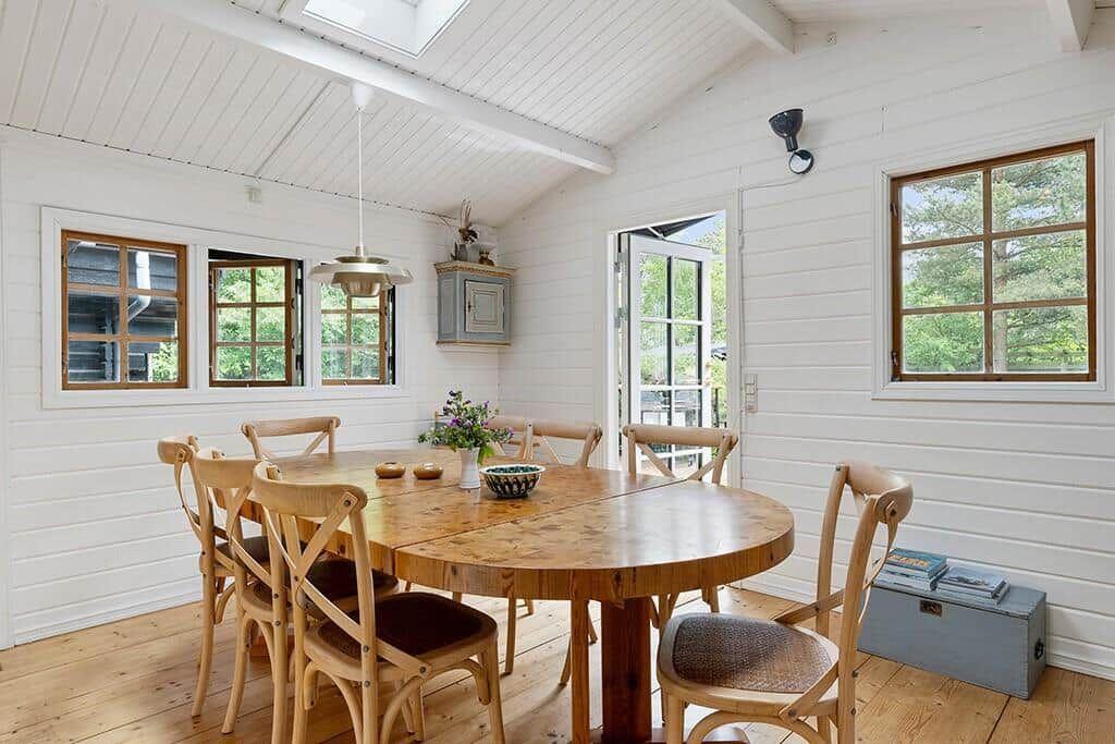 Esszimmer mit Holztisch, Stühlen und Fenstern. Dachfenster und Holzboden.