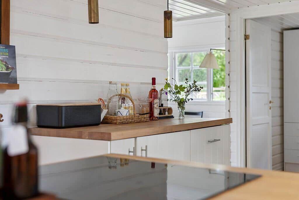 Küche mit Holzoberfläche, weißen Schränken und Fensterblick