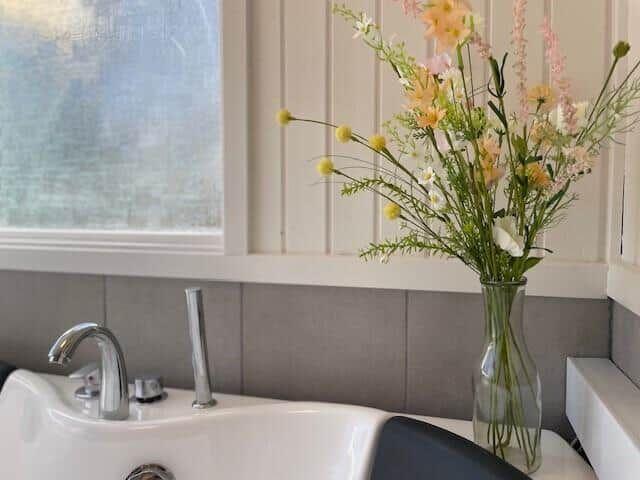 Waschbecken mit Blumenarrangement und Fenster im Badezimmer