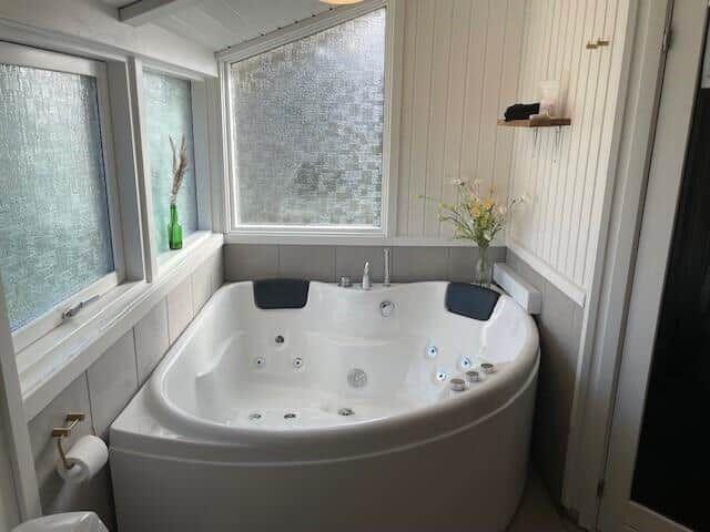 Whirlpool-Bad mit Fenstern und Blumenvase