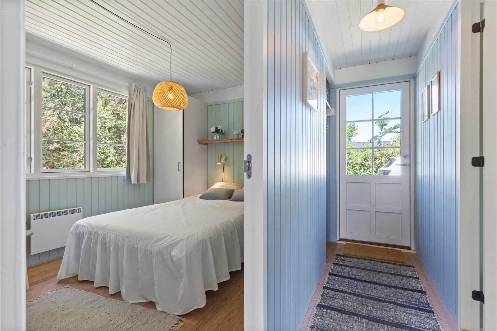 Schlafzimmer mit Bett, Fenster und Deckenleuchte. Flur mit Tür und Teppich.
