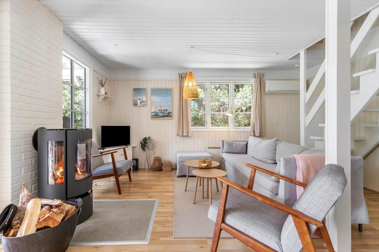 Wohnzimmer mit Kamin, Sofa und Holzboden. Fenster, Wandbild und Stufen sichtbar.
