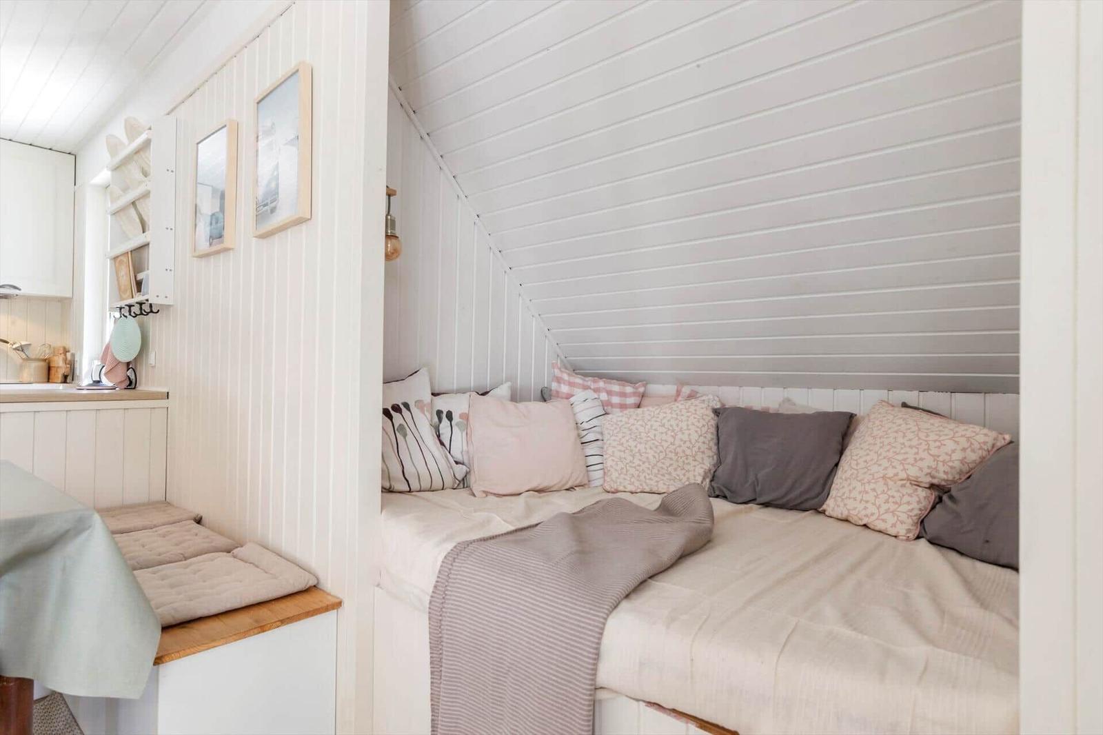 Schlafbereich mit Sitzbank, Kissen und Decke an schräger Wand