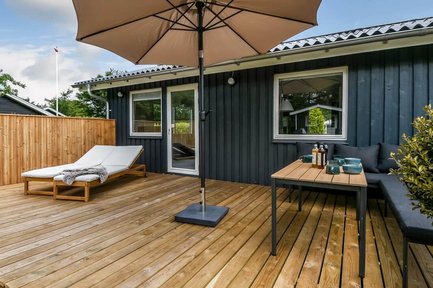 Terrasse mit Sitzgruppe, Sonnenschirm und Blick auf den Garten mit Pavillon.