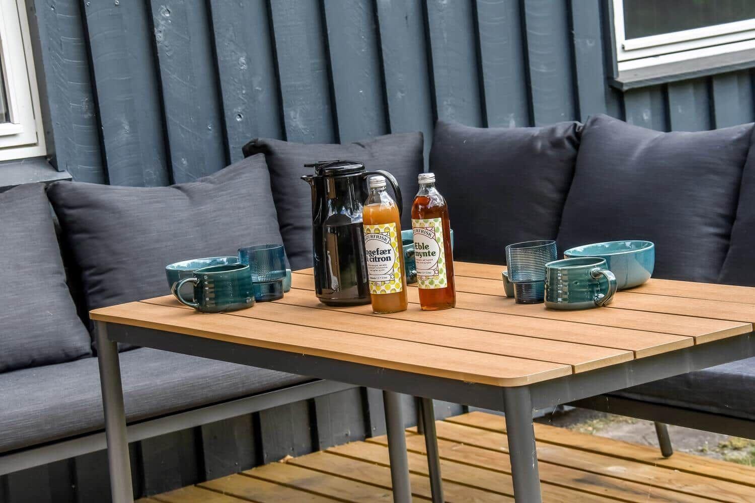 Holztisch mit Getränken und Felldecke im grünen Garten