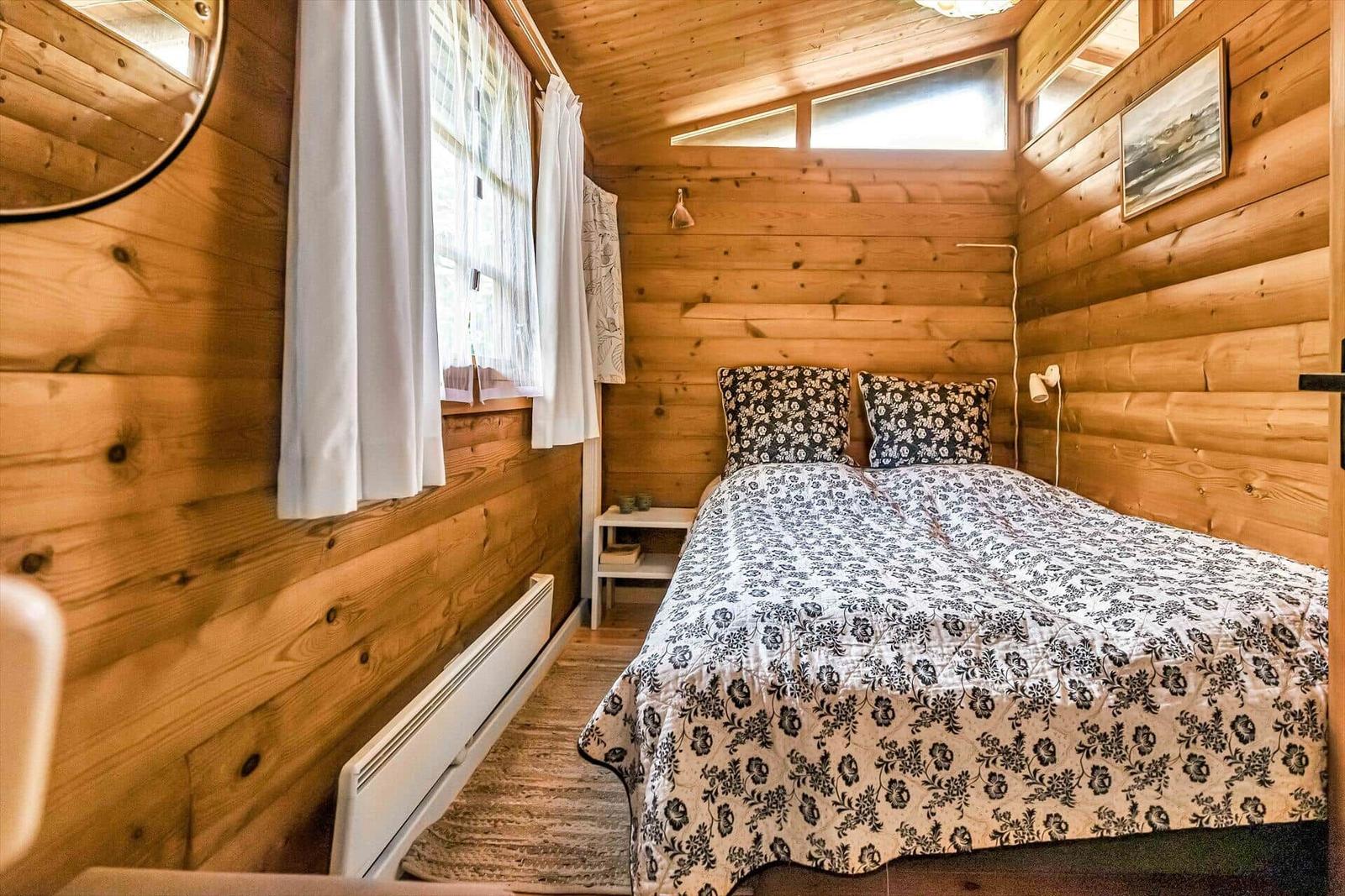 Schlafzimmer mit Holzwand, Bett, Schreibtisch und Kleiderschrank.