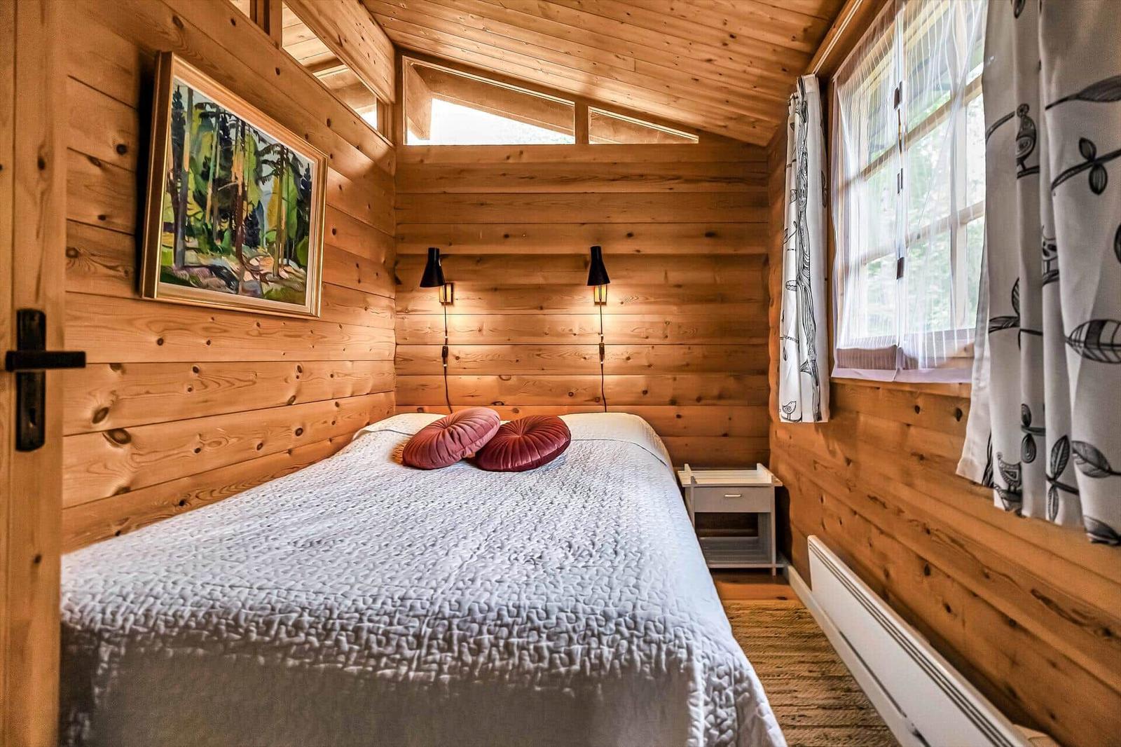 Holzhaus mit offener Tür, Blick in Küche mit weißen Schränken.