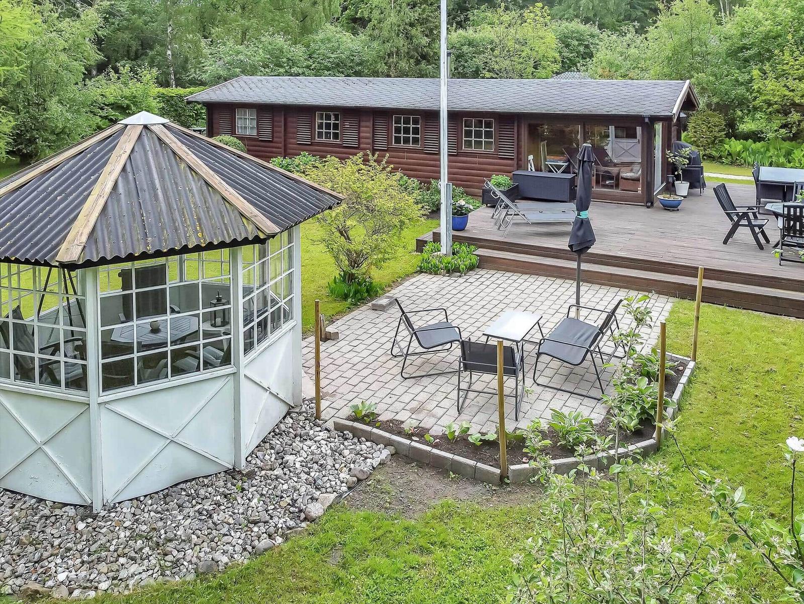 Holzhaus mit Terrasse und Garten. Weiße Pavillon und Grillplatz.