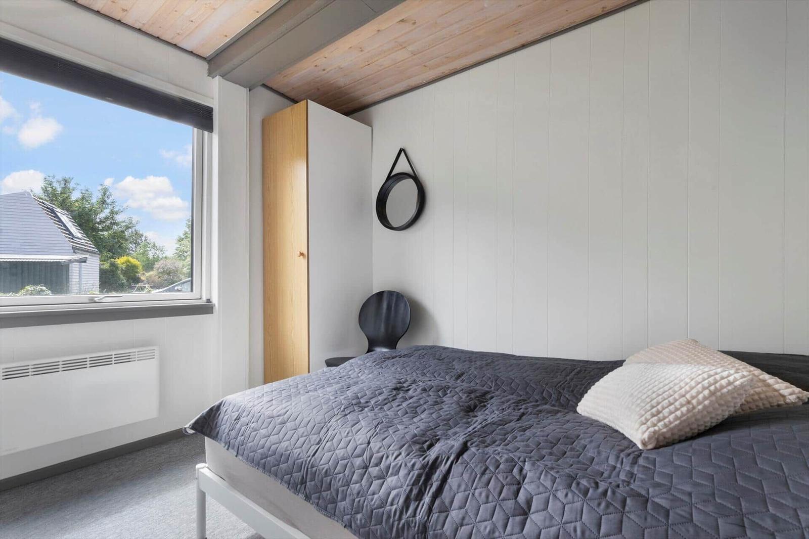 Bedroom with bed, window, and wardrobe.