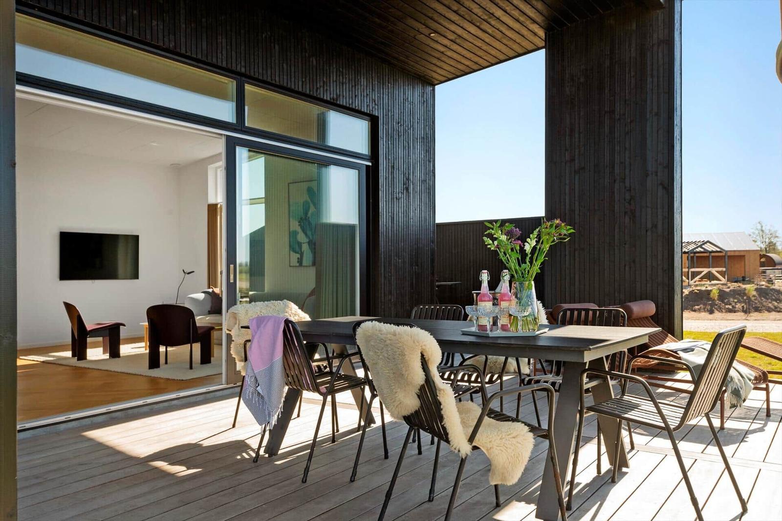 Terrasse mit Esstisch und Stühlen, Blick ins Innere des Hauses.
