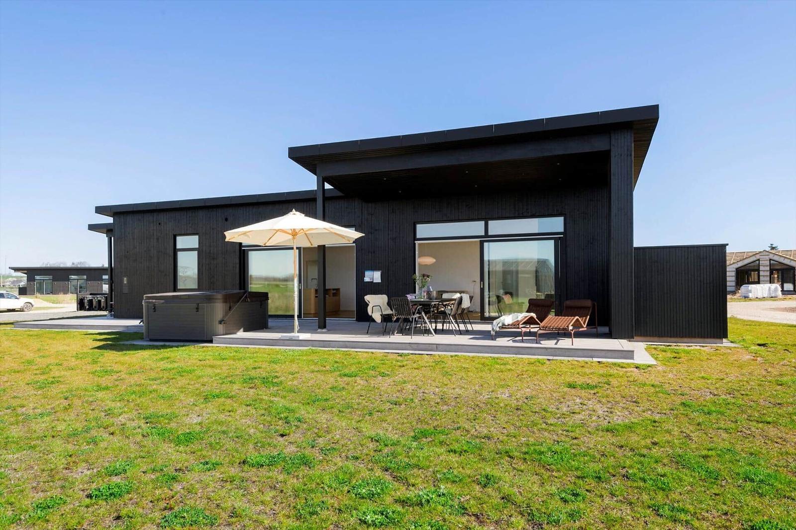 Moderne Villa mit Terrasse, Liegen, Sonnenschirm und Whirlpool im Freien.
