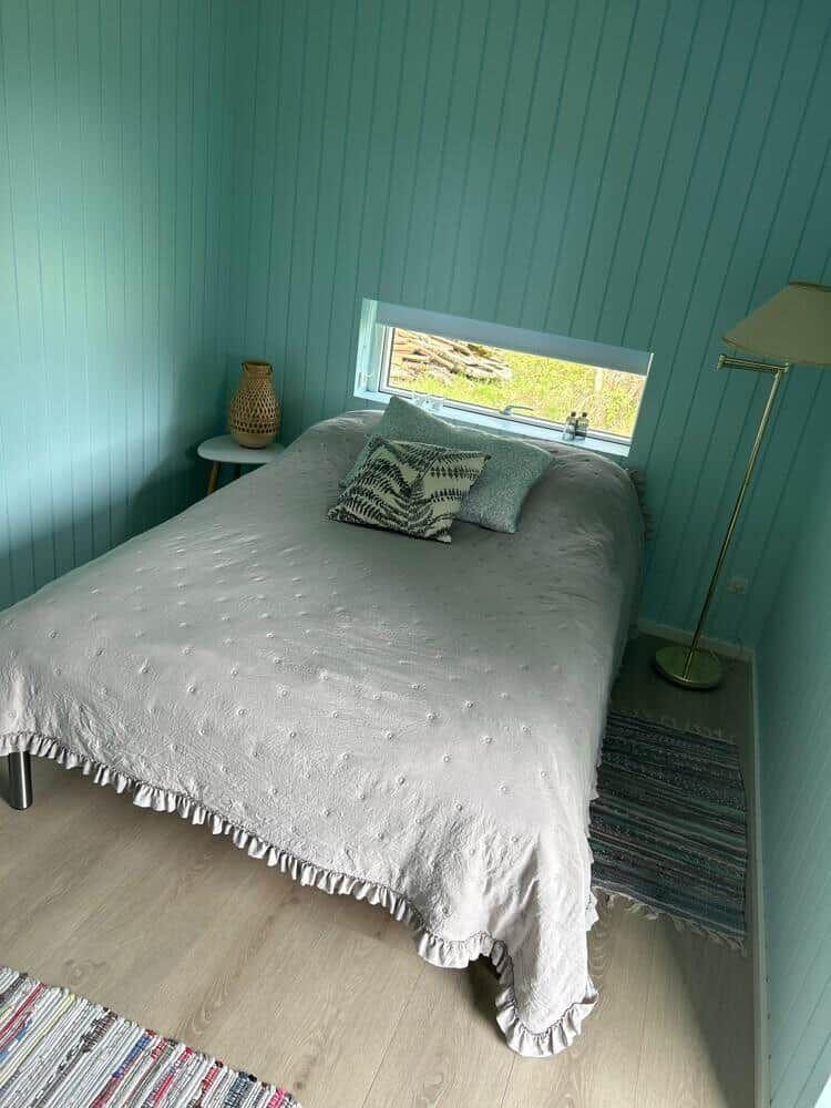 Schlafzimmer mit Bett, Fenster und Stehlampe.