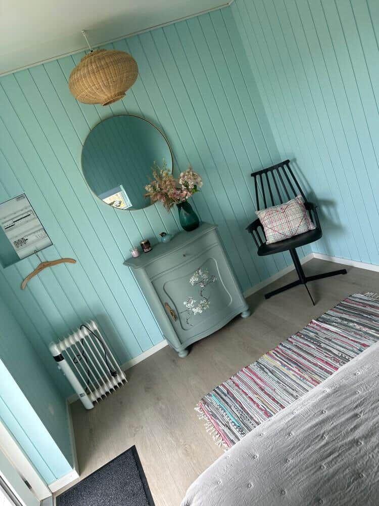 Schlafzimmer mit blauen Wänden, Schrank, Stuhl und Teppich.