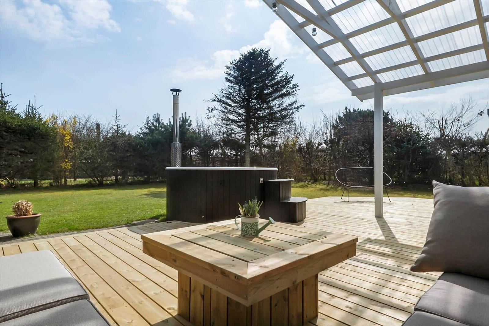 Wooden terrace with hot tub, sun cover, and garden furniture.