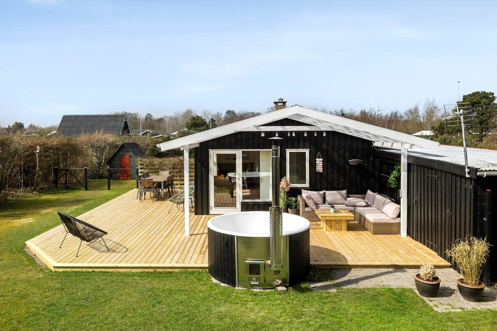 House with terrace, hot tub, and garden. Seating and table are available.