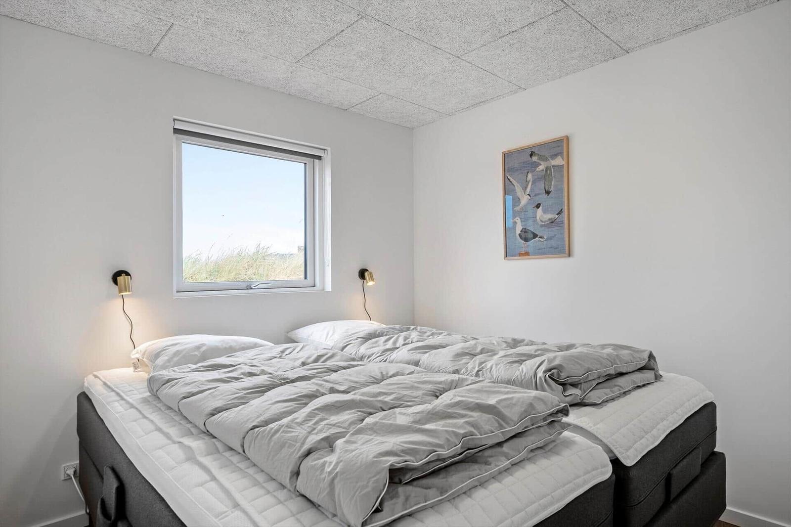 Schlafzimmer mit Doppelbett, Fenster und Wandbild mit Vögeln.