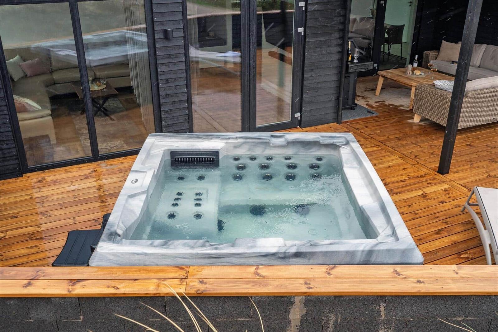 Ein Whirlpool auf einer Holzterrasse mit Blick in das Haus.