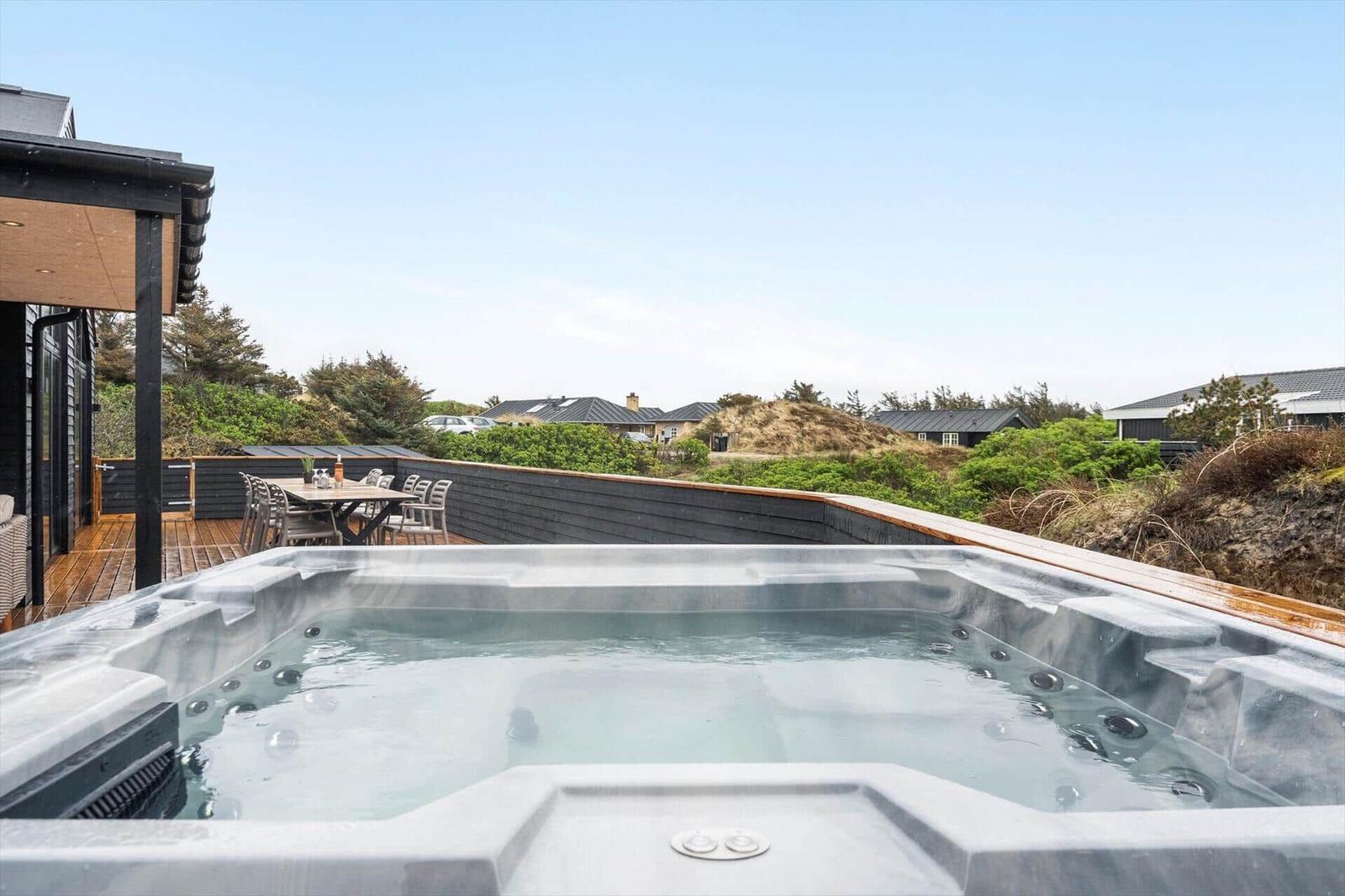 Hochwertiger Whirlpool auf Terrasse mit Blick auf Grünflächen und Häuser