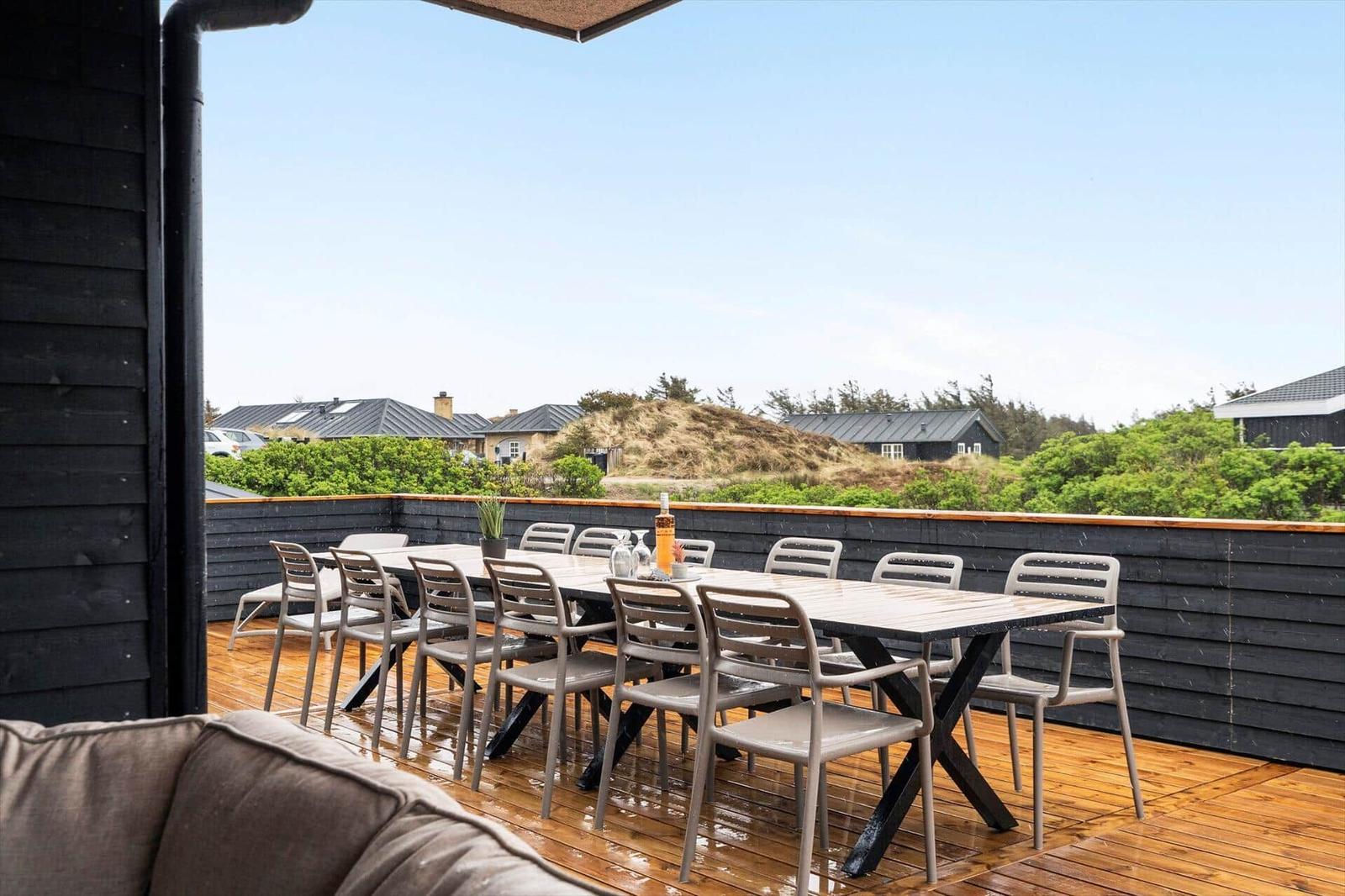 Terrasse mit Tisch und Stühlen, Blick auf Grünflächen und Häuser
