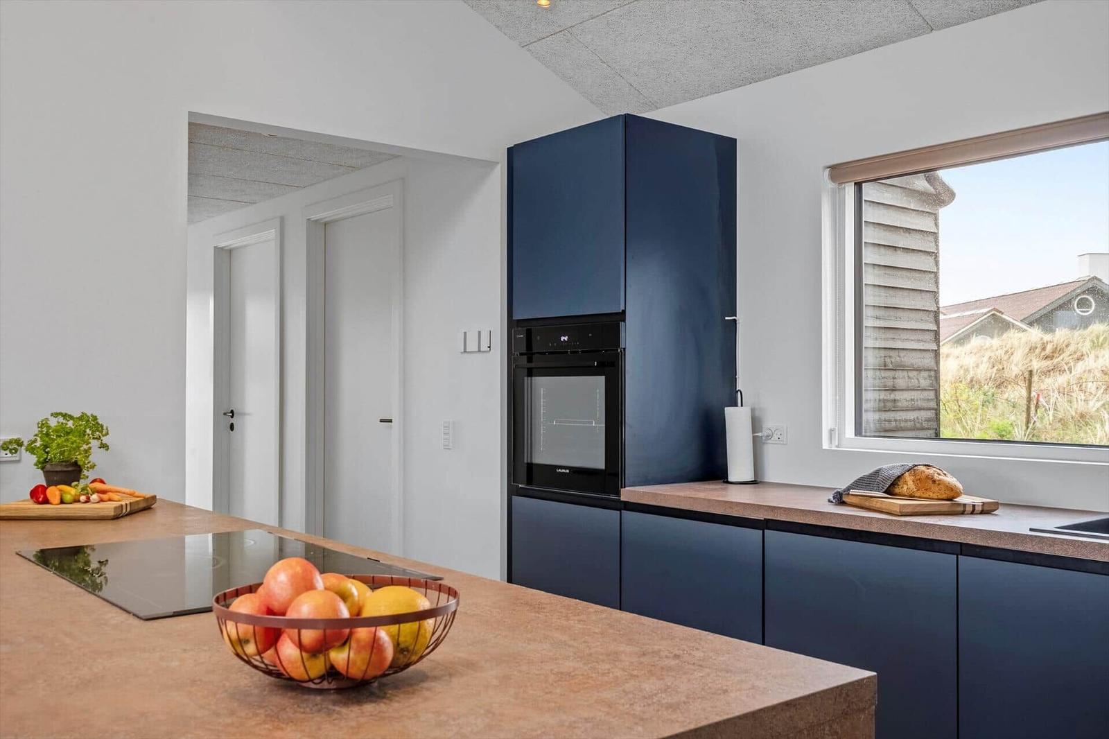 Moderne Küche mit dunkelblauen Schränken, Kücheninsel und Fensterblick.