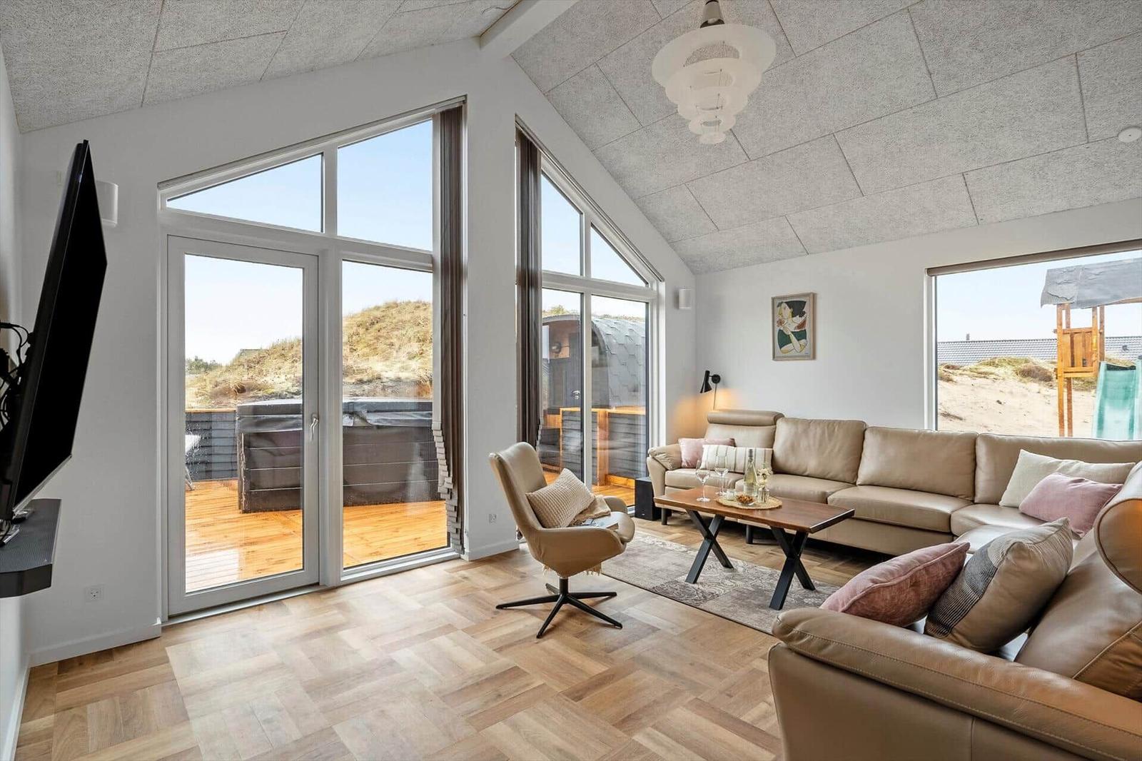 Wohnzimmer mit Sofa, Sessel und großem Fenster zur Aussicht.