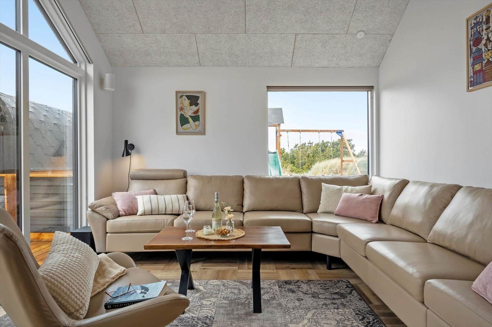 Wohnzimmer mit L-förmigem Sofa, Holztisch und Blick auf Balkon.