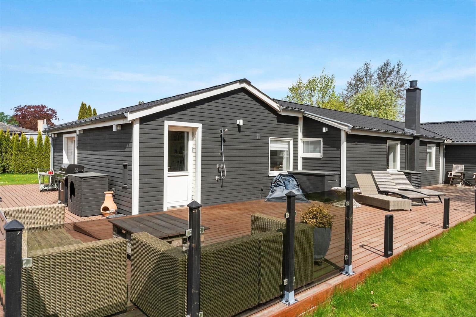 Ein Haus mit Terrasse, Liegestühlen und Grillplatz im Freien.