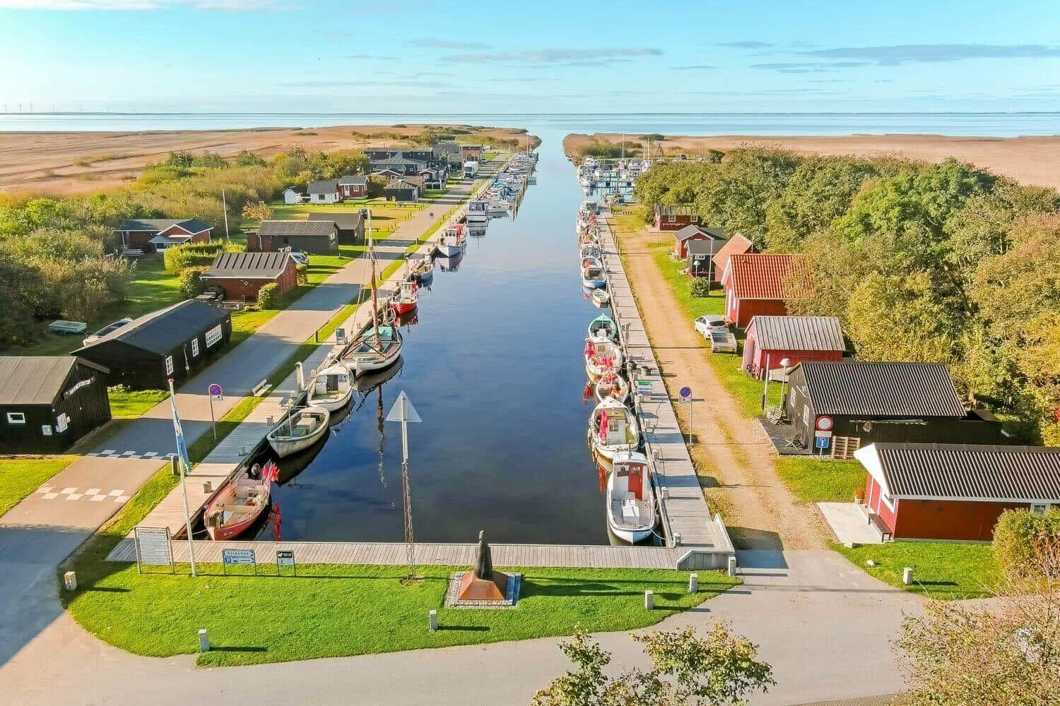 Hafen mit Booten und roten Häusern am Wasser.