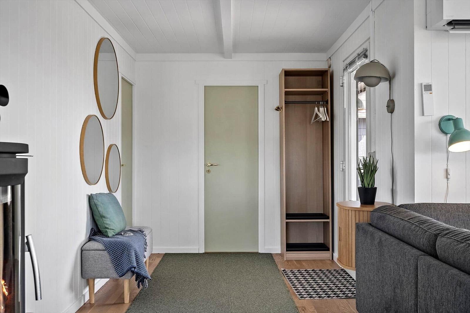 Flur mit Kleiderschrank, Wandspiegel und Sitzbank mit Kissen und Decke.