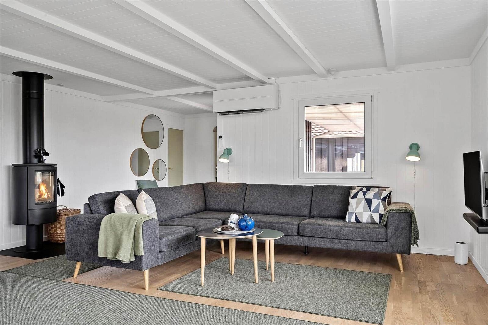 Ein Wohnzimmer mit grauem Sofa, Kamin und Holzboden.